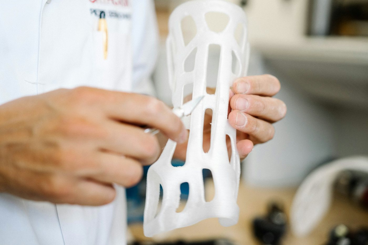 Hands holding a white 3D-printed lattice part